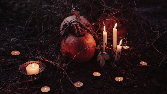 Des citrouilles et des bougies posées sur un sol de sous bois en automne
